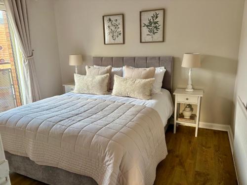 a bedroom with a large bed with white sheets and pillows at Kincraig Apartment in Ayr