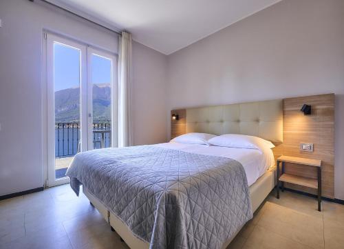 a bedroom with a large bed and a large window at Hotel Don Ferrante in Bellagio