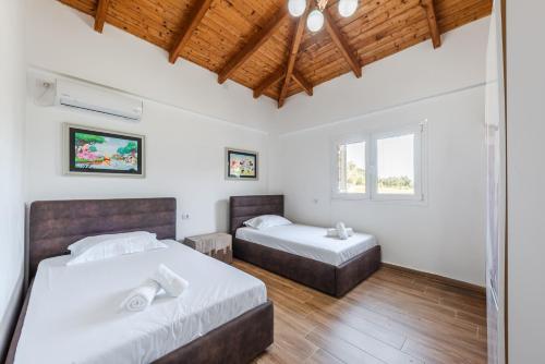 two beds in a bedroom with white walls and wooden ceilings at Siar The Small Villa by PikHost in Borsh