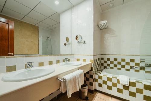a bathroom with two sinks and a tub at L'Agora Hotel in Bocairent