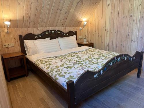 a bedroom with a large bed with a wooden wall at Namelis Bitidė, sodyba Latkrantė, Druskininkai in Latežeris