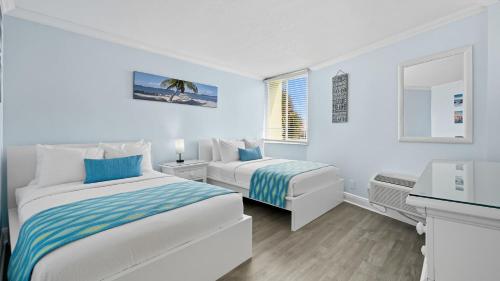 a white room with two beds and a sink at Clearwater Beach Pelican 2 in Clearwater Beach