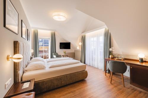 a hotel room with a bed and a desk and a bed sidx sidx sidx sidx at Hotel Friesacher`s Aniferhof in Anif