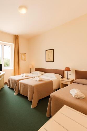 a hotel room with three beds and a television at Hotel Ariston in Piombino