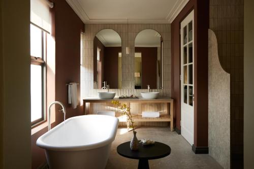 a bathroom with two sinks and a bath tub at The Manor House at Colmant in Franschhoek