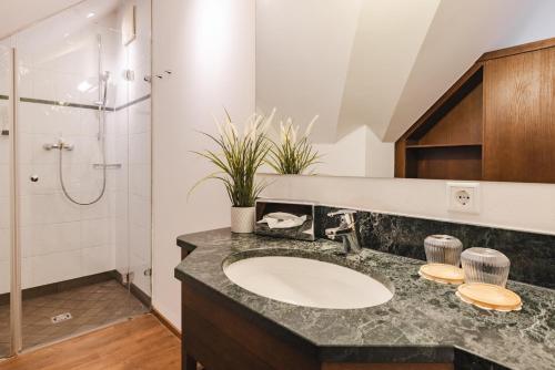 a bathroom with a sink and a shower at Hotel Friesacher`s Aniferhof in Anif