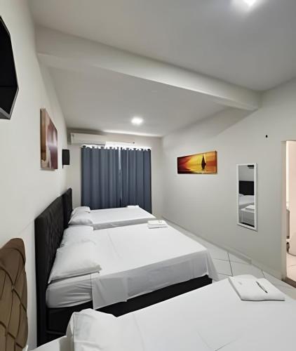 a row of beds in a room with white walls at Apto. Aconchego familiar c/cozinha até 06 pessoas in Rio Branco