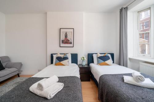 two twin beds in a room with a couch at 5-Star 2BE Apt in Central London Perfect 2026 in London