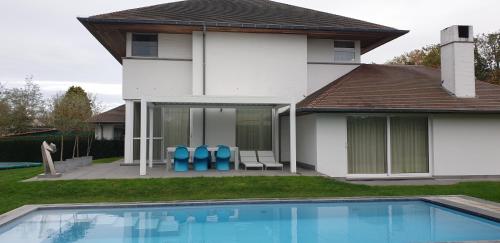 a house with a swimming pool and two blue chairs at Thibault 1 in Gistel