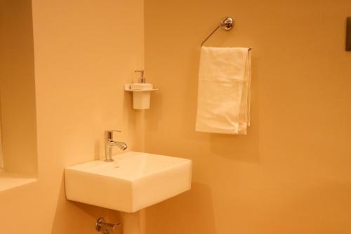 a bathroom with a white sink and a towel at Le Sara's Nest in Pondicherry