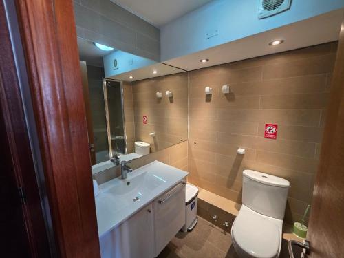 a bathroom with a toilet and a sink and a mirror at Departamento Lago Vichuquen in Vichuquén Lake