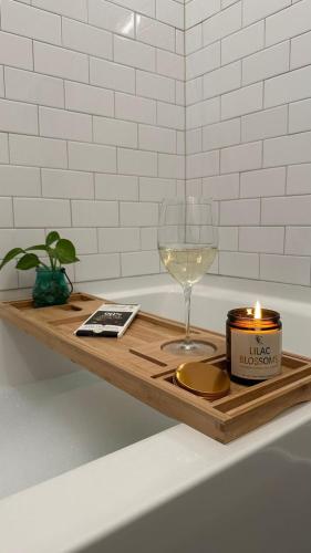 a candle and a glass of wine on a tray in a bath tub at Modern apt in Cincy stadiums and with river views in Cincinnati