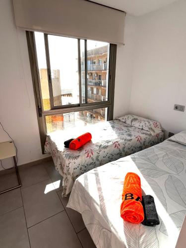 two beds in a room with a large window at Apartamentos Marjal 3 in Guardamar del Segura