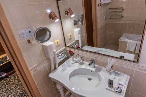 ein Badezimmer mit einem weißen Waschbecken und einem Spiegel in der Unterkunft Premier Hotel Palazzo in Poltawa