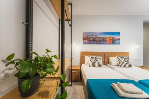 a bedroom with two beds and a potted plant at NEW - Only Suites Unit 6 - Modern 2-Bedroom apartment with common heated Jacuzzi by SF Homes in St. Julianʼs