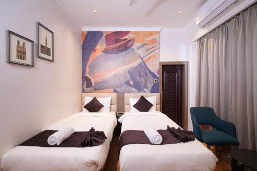 two beds in a hotel room with a painting on the wall at NE Heritage Residency in Guwahati