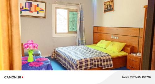 a small bedroom with a bed and a vase of flowers at Hôtel Kolou Wyam in Tcharé
