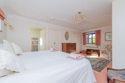 a bedroom with a large white bed with pink towels on it at Willow Cottage in North Lydbury