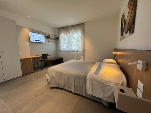 a bedroom with a bed and a desk and a television at B&B Room47 in Alba Adriatica