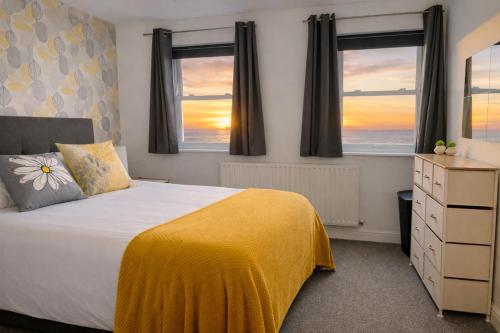 a bedroom with a bed and two windows at Sunset House On The Beach in Maryport