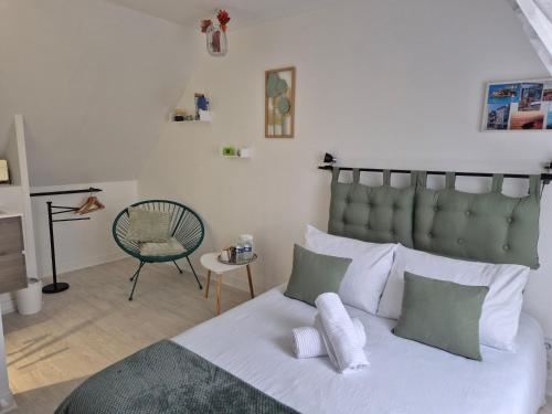 a bedroom with a bed with white pillows and a chair at Chez Ninie in Le Cloître-Saint-Thégonnec