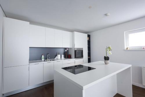 a white kitchen with white cabinets and a sink at Aeris Residence Panoramic View in Sarajevo