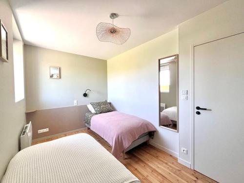 a bedroom with two beds and a mirror at Le Petit Héros Gîte in Courlay