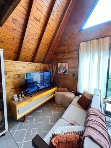 a living room with a couch and a flat screen tv at Chalé Sol Nascente - Vista espetacular próximo as melhores praias de Floripa in Florianópolis