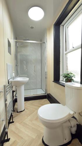 a bathroom with a toilet and a sink and a shower at Newcastle CITY APT35,FREE STREET PARKING,4 BEDROOM HOUSE,8 SINGLE BEDS,FULL KITCHEN,ALL ROOMS WITH TVs,NETFLIX in Newcastle upon Tyne