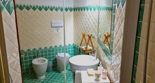 a green tiled bathroom with a toilet and a sink at Villa Bellavista Palau in Barrabisa