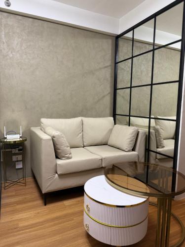 a living room with a white couch and a glass table at The UrbanNest - 1BR Condo in Marina Spatial, Dumaguete with free fast WiFi and Pool in Piapi
