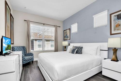 a bedroom with a white bed and a tv at 5 BR 6 BA Luxury Villa 5 min to Disneyworld Hot Tub & BBQ 112 in Orlando