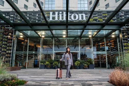 kobieta idąca przed budynkiem z walizką w obiekcie Hilton Sofia w mieście Sofia