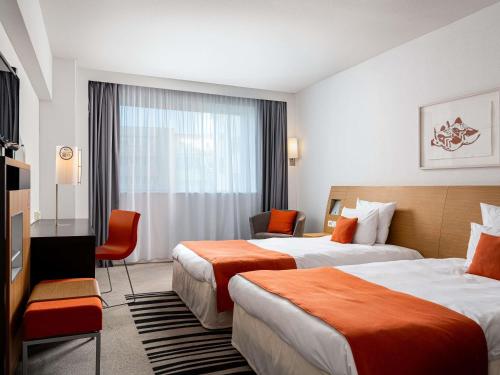a hotel room with two beds and a television at Novotel Bucharest City Centre in Bucharest