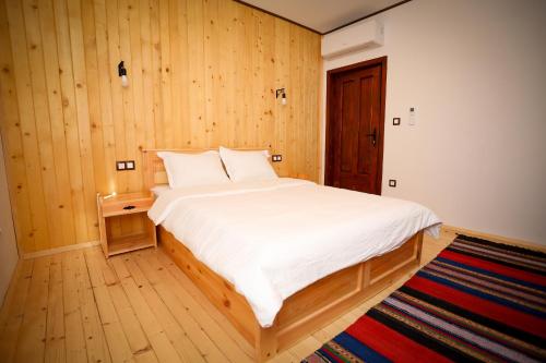 a bedroom with a large white bed with a wooden wall at Родопчани Старцево in Starzewo