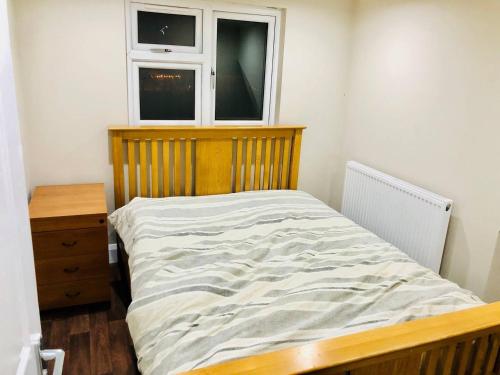 a bed in a bedroom with two windows at Small 3 Bed Flat near Heathrow in Staines