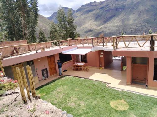 a man standing on the balcony of a house with a bridge at Hatun Apu Center Casa de Ayahuasca y San Pedro in Pisac
