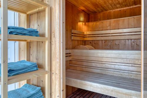 a sauna with wooden walls and wooden shelves at Villa Argonne - Cottages & Spa Privatif in Ouville-la-Rivière
