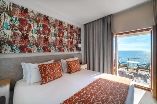 a bedroom with a bed with a view of the ocean at Castelo Guest House in Carvoeiro