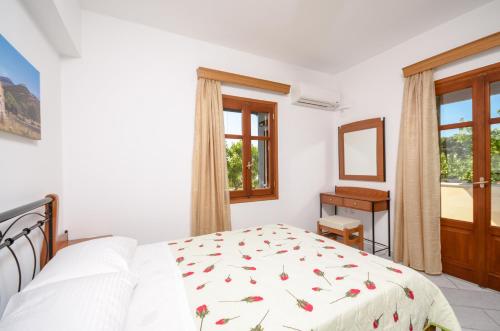 a white bedroom with a bed and a window at Naxos Cottage in Káto Sangríon