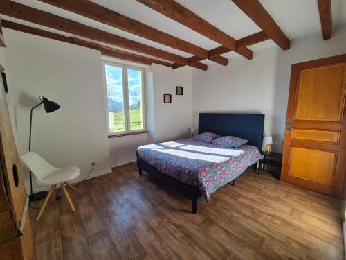 a bedroom with a bed and a chair and a window at Maison au calme en Chartreuse in Miribel-les-Échelles
