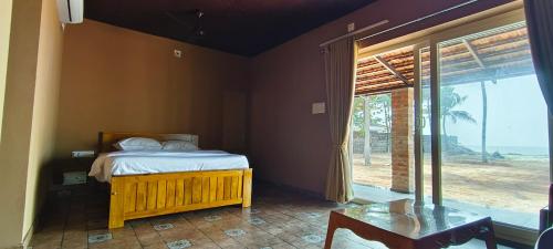 a bedroom with a bed and a large window at Agastya Beach House in Ullāl