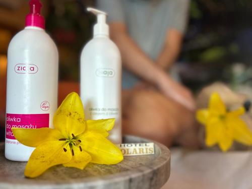 two bottles of soap and a yellow flower on a counter at Hotel Polaris in Świnoujście