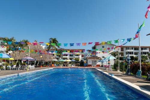 a pool at a resort with flags and umbrellas at departamento de lujo, Puerto Vallarta. Mexico in Puerto Vallarta