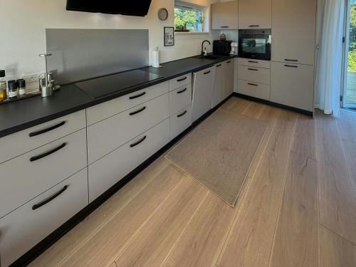 a kitchen with white cabinets and a wooden floor at Renovated Holiday Home With Sea View In Skåstrup in Bogense