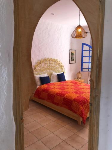 a bedroom with a bed with a red comforter at Villa Thalassa in Oualidia