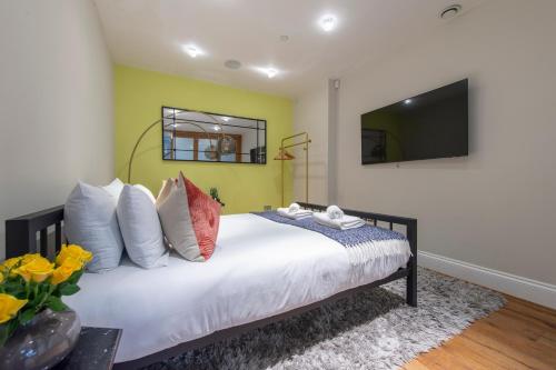 a bedroom with a bed with a tv on the wall at Soho Harmony Haven: Chic 2-Bed, 2-Bath Urban Retreat in London