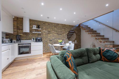 a living room with a green couch and a kitchen at Soho Harmony Haven: Chic 2-Bed, 2-Bath Urban Retreat in London