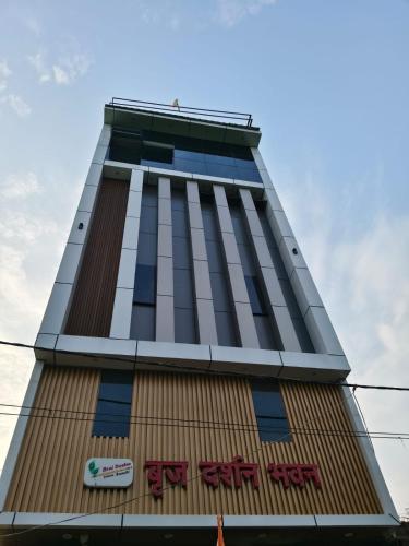 a tall building with a sign on it at Braj Darshan Bhawan in Jāmb
