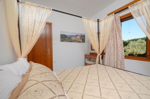 a bedroom with a bed with curtains and a window at Naxos Cottage in Káto Sangríon
